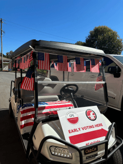 a golf cart decorated with American flags and a sign that reads "early voting here"