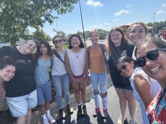 a group of young people smile together while taking a selfie