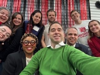 a group of people of all ages taking a selfie in front of a red and black wall
