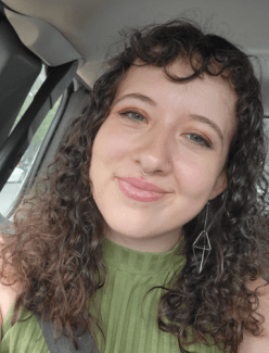 a young white woman with curly brown hair wearing a green top