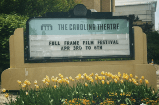 a marquee that reads "Carolina Theatre" with tulips in front