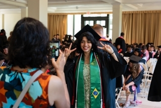 a graduate in regalia takes a picture indoors