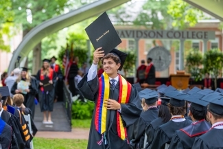 Commencement 2025 student holding up diploma