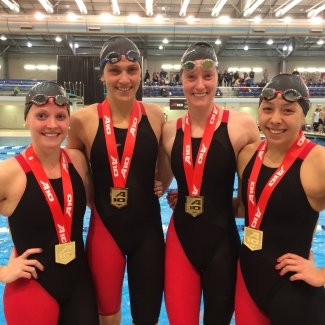 four. young women wear medals while wearing swimming uniforms