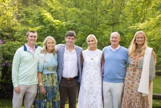 a family standing together in summery clothes in front of a green landscape