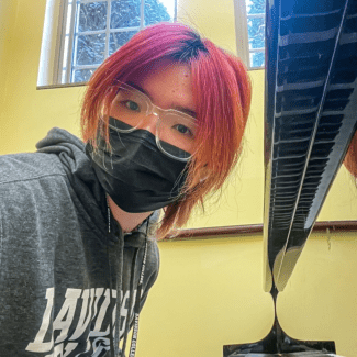 a young Asian woman with red hair wearing a mask while playing the piano