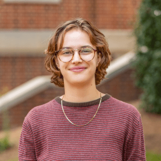 a young white woman with short hair wearing a red top and glasses