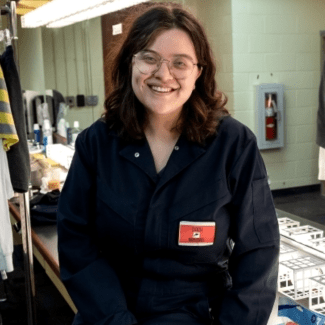 a young woman with dark hair wearing glasses backstage of a theater