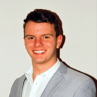 a young white man with brown hair wearing a collared shirt and jacket