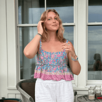 a young white woman wearing white linen pants and a floral top