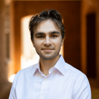 a young white man with brown hair wearing a collared white shirt