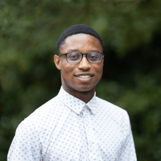 a young Black man wearing glasses and a white collared shirt