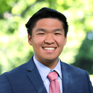 a young man with dark hair wearing a suit and tie