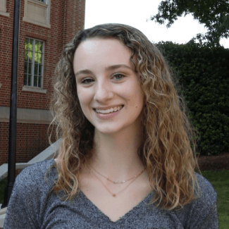 a young white woman with curly blonde hair wearing a grey top