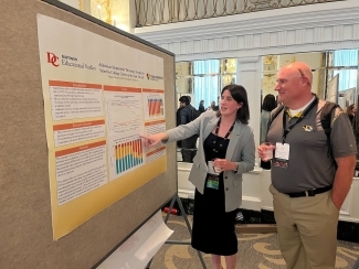 a young woman presents a poster to an older man 