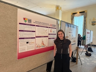 a young woman stands in front of a poster presentation