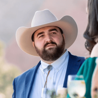 a young white man wearing a suit and cowboy hat