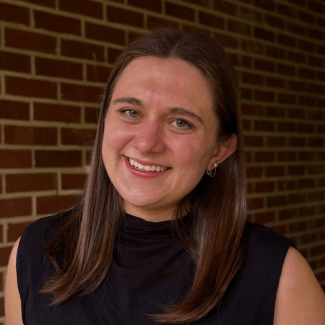 a young white woman wearing a black turtleneck with brown hair smiling