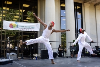 two young Black men dance on a stage