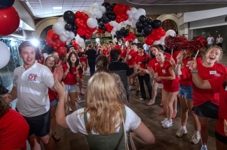 a group of students in red and white shirts cheer around a young woman