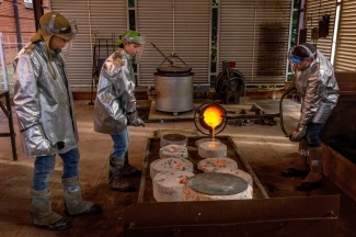 a group of students in heavy gear work with bronze foundry