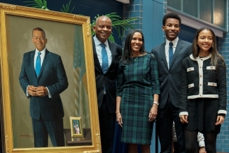 a young Black family stands around a portrait in a gallery