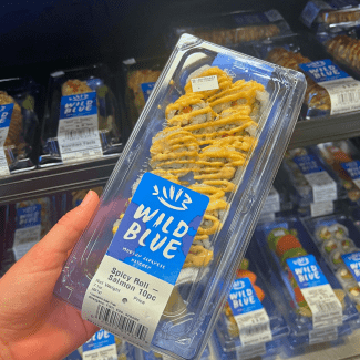 a to-go box of sushi in front of a fridge