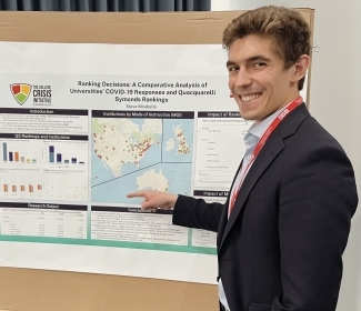 a young man presents a poster presentation at a conference