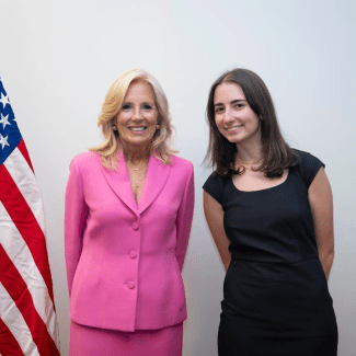 an older white woman in a pink suit stands with a younger white woman in a black dress