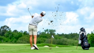 a young man swings and hits a golf shot