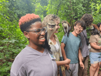a young Black woman smiles while holding a monkey