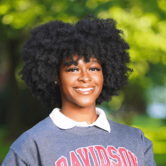 a young Black woman wearing a collared shirt underneath a Davidson College sweatshirt