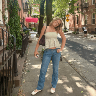 a young woman wearing jeans and a flowy top on a street in a city