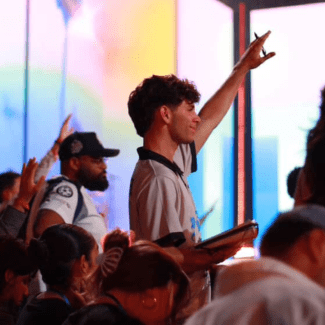 a young man in a crowd raising his hand