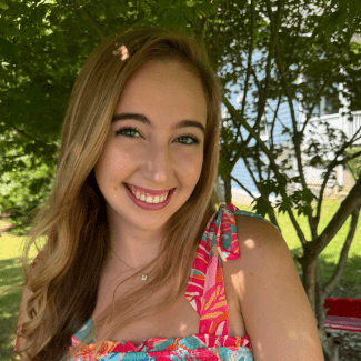 a young woman with blonde hair wearing a floral pink dress on a sunny day