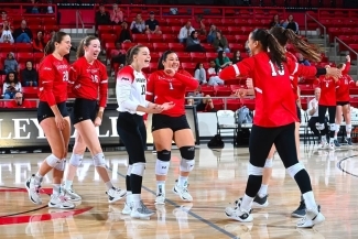 a group of young women cheer while playing volleyball