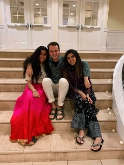 two young women and a young man smile together while sitting on a staircase in an academic building
