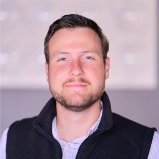 a young white man wearing a collared shirt and vest