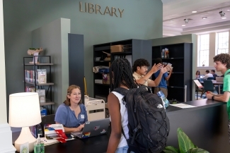 a reference desk at a library where students and staff are gathered having a conversation