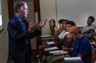 a man speaks to a classroom of college students