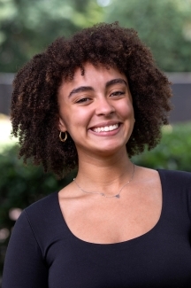 Female student smiles for the camera dark curly hair and a black shirt