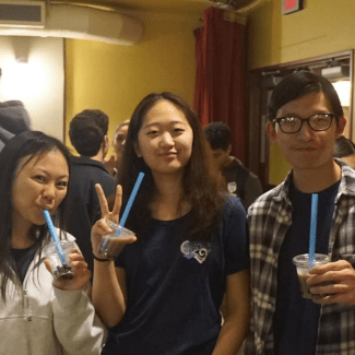 three young people smile while drinking boba