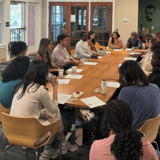 a group of students sit around a conference room table with tea