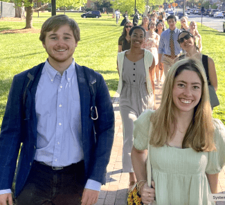 Smiling group of students wearing suits and spring dresses outdoors