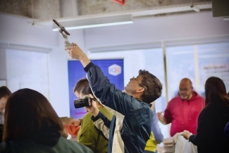 a young man films an event using a camera and a phone on a tripod