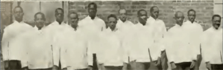 Eleven adult black men uniformed in white shirts and dark pants