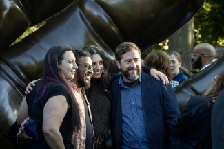 Smiling group of young adults in front of the sculpture