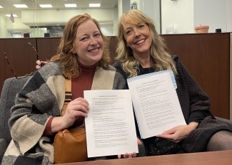 Hannah (left) and previous QED owner, Kambri Crews smile holding the business purchase paperwork