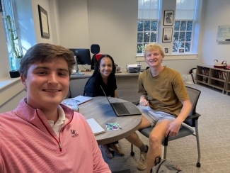 two students meet with a staff member in an office