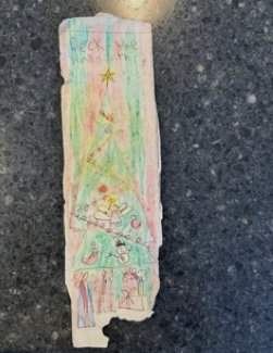 A bookmark made by a young child with a hand-drawn christmas tree in crayon